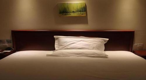 a bed with a wooden headboard and a white pillow at GreenTree Inn Beijing East Yizhuang District Second Kechuang Street Express Hotel in Beijing