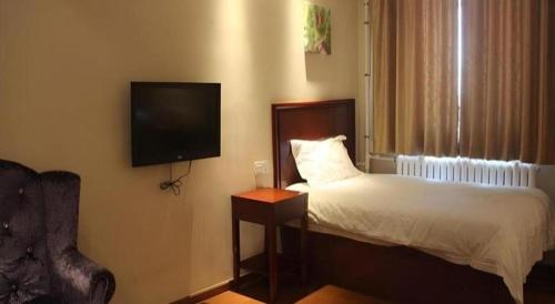 a bedroom with a bed and a flat screen tv at GreenTree Inn Beijing East Yizhuang District Second Kechuang Street Express Hotel in Beijing