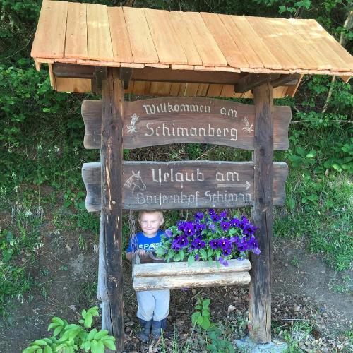 a little child standing in a sign with flowers at Erlebnishof Schiman in Kirchbach