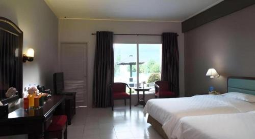 a hotel room with a bed and a desk and a table at Hotel Niagara Parapat in Parapat