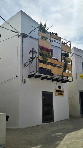 a white building with a balcony with plants on it at Community Rooms & Wine in Favara