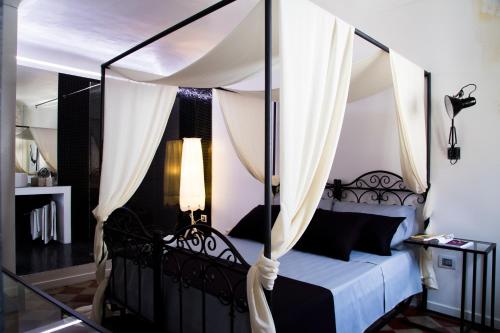 a bedroom with a canopy bed with white curtains at Community Rooms & Wine in Favara