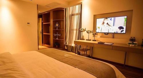 a bedroom with a bed and a desk with a television at GreenTree Inn Xi'an Yanta District Dayanta Furongyuan Hotel in Xi'an