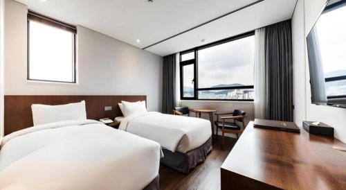 a hotel room with two beds and a table at CS Premier Hotel in Seoul