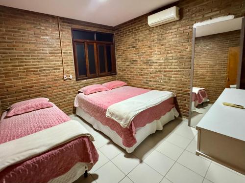 a bedroom with two beds and a brick wall at Casa Praia do Frances in Marechal Deodoro