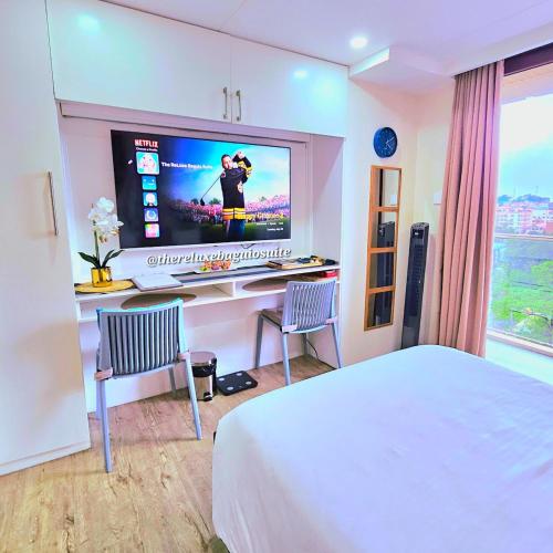 a hotel room with a bed and a tv on a wall at The ReLuxe Baguio Suite CityHub in Baguio
