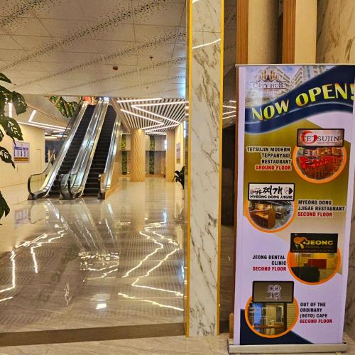 a now open sign in a hallway with an escalator at The ReLuxe Baguio Suite CityHub in Baguio