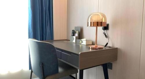 a desk with a lamp and a chair in a room at Golden Central Hotel Shenzhen in Shenzhen