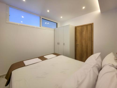 a bedroom with a large white bed and a window at ALEXANDROS apartments by SDR in Paralia Katerinis