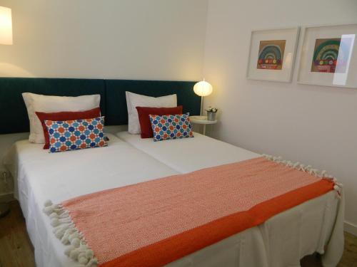 um quarto com uma grande cama branca com almofadas em Enjoy Casa do Forte Apartment em Lisboa