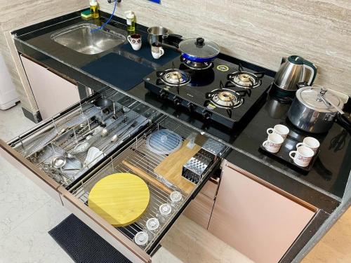 a kitchen counter with a stove top with pots and pans at Lakeside Retreat 2 BHK in Powai in Mumbai