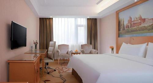 a hotel room with a bed and a desk and a television at Vienna Hotel Shenzhen Bao'an Airport Taoyuanju Pingluanshan Metro Station in Shenzhen