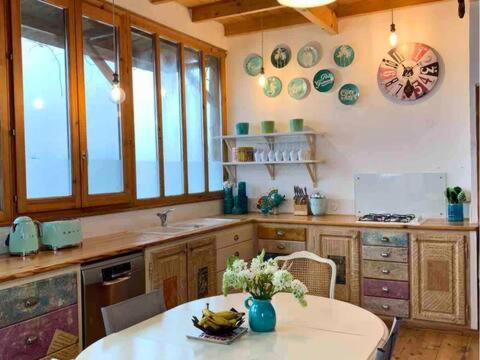 une cuisine avec une table et une horloge au mur dans l'établissement Maison Lily en Provence - Gonfaron - 4ch, à Gonfaron