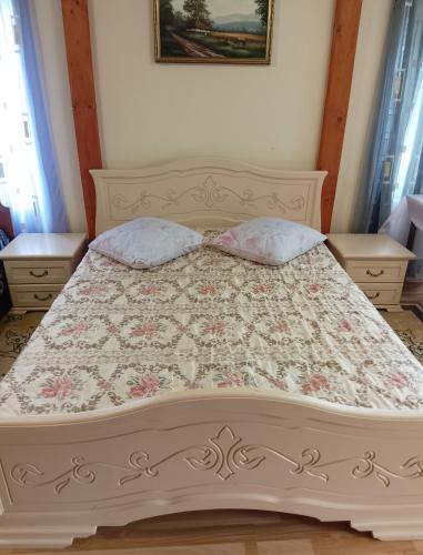 a bed with a floral bedspread and two pillows at Садиба Сергія in Sinyak
