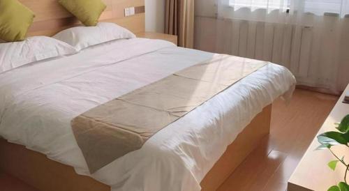 a large bed with white sheets and pillows at GreenTree Inn Langfang GuAn County Xinyuan Street Express Hotel in Langfang