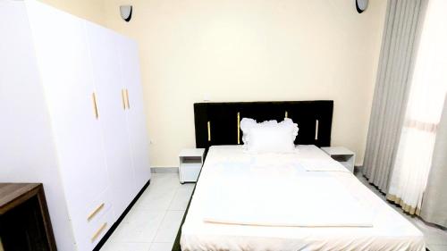 a bedroom with a large white bed with a black headboard at Kigali Nice Apartment in Kigali