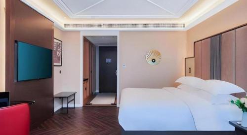 a bedroom with a large white bed and a desk at Jinjiang Metropolo Hotel - Taizhou Wanda Plaza in Taizhou