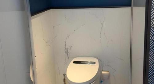 a bathroom with a toilet in a white wall at Jinjiang Metropolo Hotel - Taizhou Wanda Plaza in Taizhou