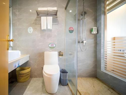 a bathroom with a toilet and a glass shower at GreenTree Alliance Foshan West Station Luowu Road Hotel in Foshan