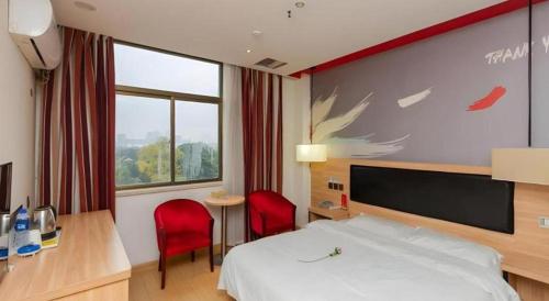 a hotel room with a bed and two red chairs at Thank Inn Hotel Jiangsu Suzhou Luzhi Ancient Town Scenic Area in Suzhou