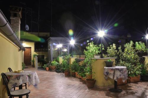 a patio with tables and potted plants at night at Locanda Modigliani in Ferrara
