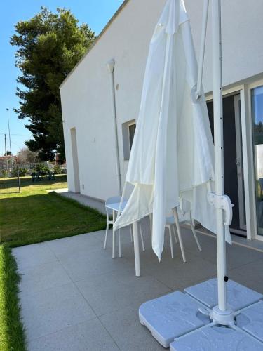 a white umbrella and chairs in front of a building at Villetta Maria in Porto Cesareo