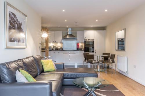 ein Wohnzimmer mit einem Sofa und einer Küche in der Unterkunft House of Fisher - Equinox Place in Farnborough
