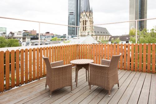 
a wooden table with chairs and a patio with a view of the water at Hotel Villa Florentina in Frankfurt/Main
