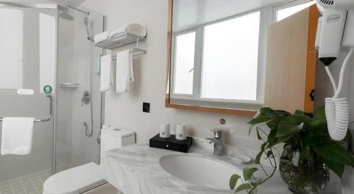a bathroom with a sink and a toilet and a window at GreenTree Inn Wuhu Eshan Road University City in Wuhu