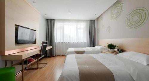 a hotel room with two beds and a desk and a television at GreenTree Inn Wuhu Eshan Road University City in Wuhu
