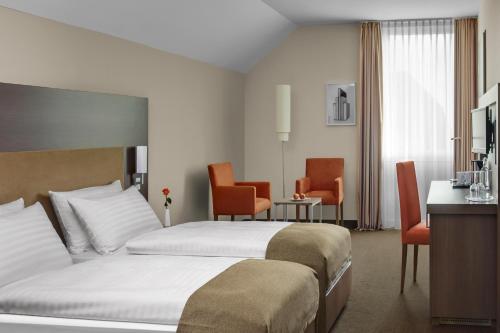 a hotel room with two beds and chairs at IntercityHotel Darmstadt in Darmstadt