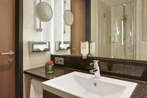 a bathroom with a sink and a mirror at IntercityHotel Darmstadt in Darmstadt