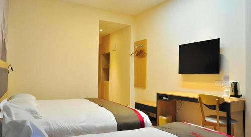 a hotel room with a bed and a desk with a television at Thank Hotel Jiangxi Jiujiang Lianxi District Railway Station Square in Jiujiang