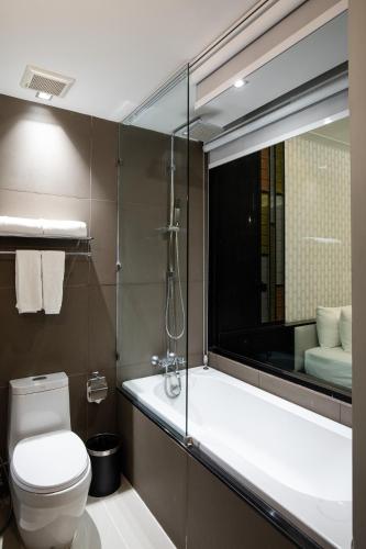 a bathroom with a toilet and a large mirror at De Chai Oriental Nimman - SHA Plus in Chiang Mai