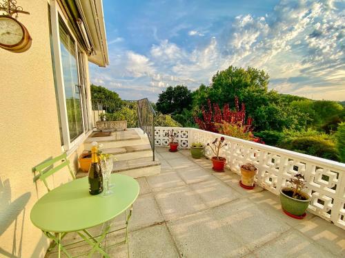 a patio with a green table and some potted plants at Leighwood Cottage in Paignton