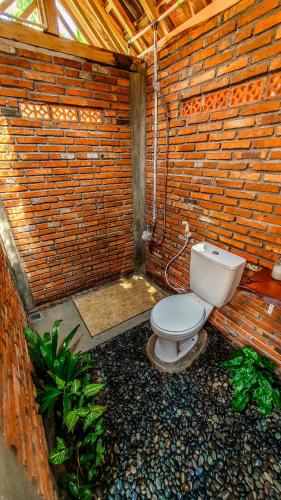 a bathroom with a toilet in a brick wall at Rumah Gaharu - Kulon 