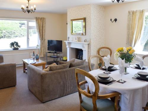 a living room with a table and chairs and a fireplace at Cherrytree Cottage in Loftus