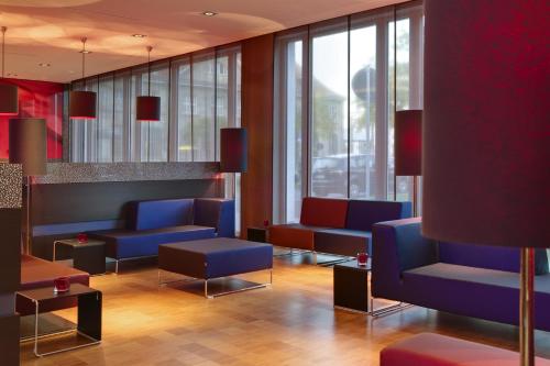 a waiting room with blue chairs and windows at IntercityHotel Darmstadt in Darmstadt