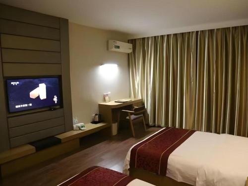a hotel room with a bed and a desk and a television at GreenTree Inn Gaoyou Government in Yangzhou
