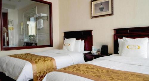 a hotel room with two beds and a mirror at Datong Tiangui International Hotel in Datong
