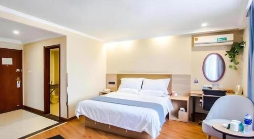 a bedroom with a bed and a desk and a chair at GreenTree Inn Jiaxing Tongxiang Tudian Express Hotel in Jiaxing