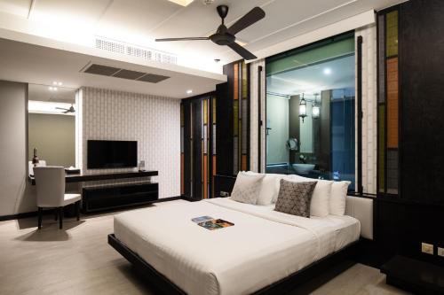 a bedroom with a large white bed and a desk at De Chai Oriental Nimman - SHA Plus in Chiang Mai