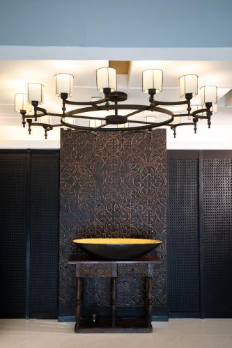 a chandelier in a room with a tub on a wall at De Chai Oriental Nimman - SHA Plus in Chiang Mai