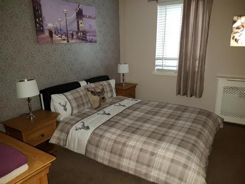 a bedroom with a bed with a plaid blanket at Lascala City Apartment in Inverness