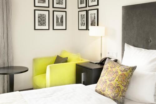 a hotel room with a bed and a yellow chair at Hotel Hamburger Hof in Frankfurt/Main