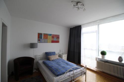 ein Schlafzimmer mit einem Bett, einem Stuhl und einem Fenster in der Unterkunft Apartments Sankt Augustin in Sankt Augustin