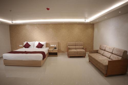 a bedroom with a bed and a chair and a couch at Hotel Grand Courtyard Pala in Pala