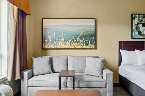 a living room with a couch and a bed at Ramada by Wyndham Drumheller Hotel & Suites in Drumheller