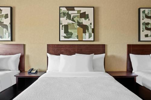 a hotel room with a large bed with white sheets at Ramada by Wyndham Drumheller Hotel & Suites in Drumheller
