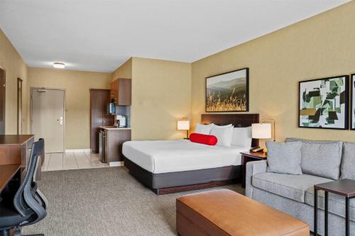 a hotel room with a bed and a couch at Ramada by Wyndham Drumheller Hotel & Suites in Drumheller
